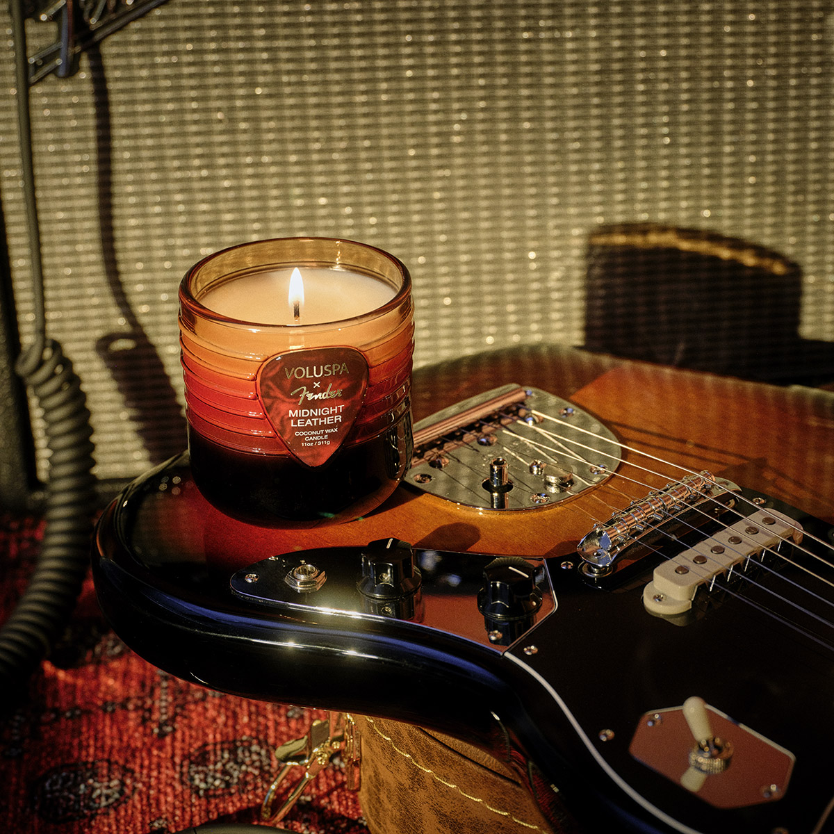 Vela Midnight Leather ao lado de uma guitarra Fender
