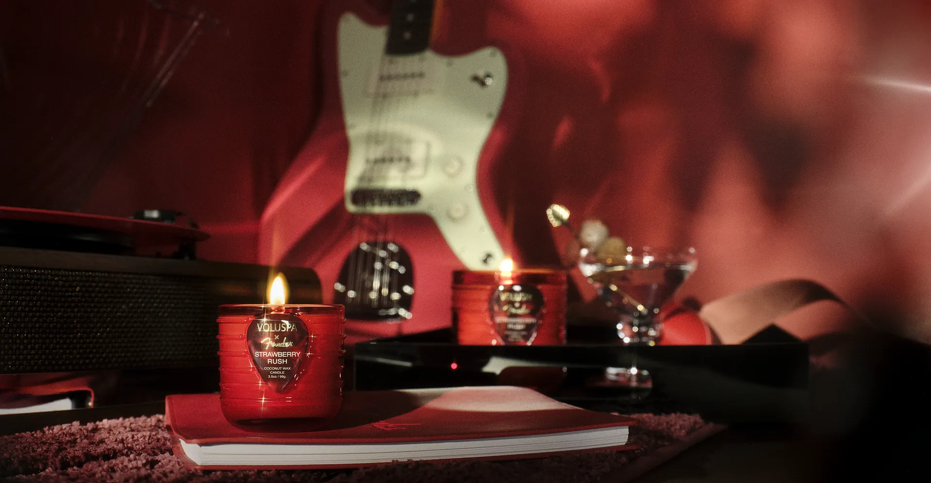 Velas Voluspa × Fender ao lado de uma guitarra